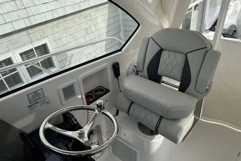 Slide: The Image of 2026 Pursuit OS 325 Offshore helm with luxury seating and steering wheel. - 7
