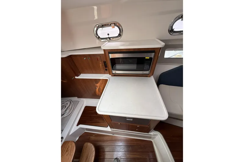 Slide: The Image of 2026 Pursuit OS 325 Offshore interior with microwave and wooden cabinetry. - 9