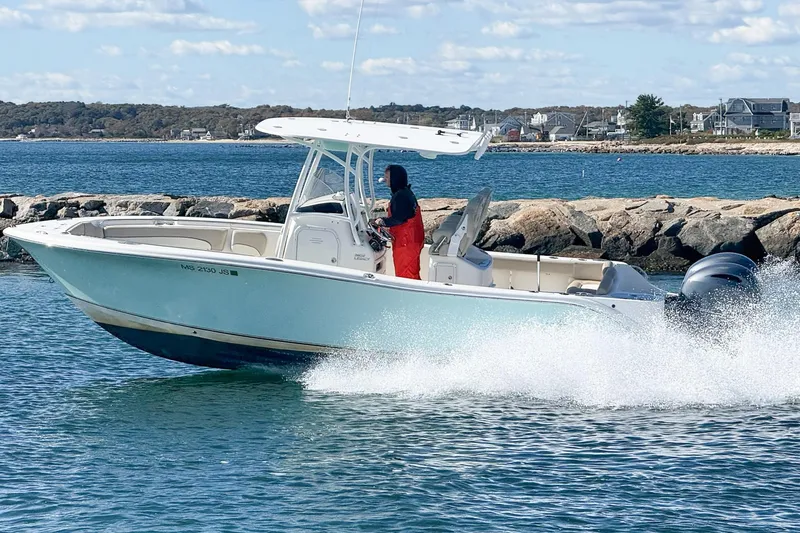 The Image of 2017 NauticStar 2602 Legacy boat cruising on water near rocky shoreline. - 0