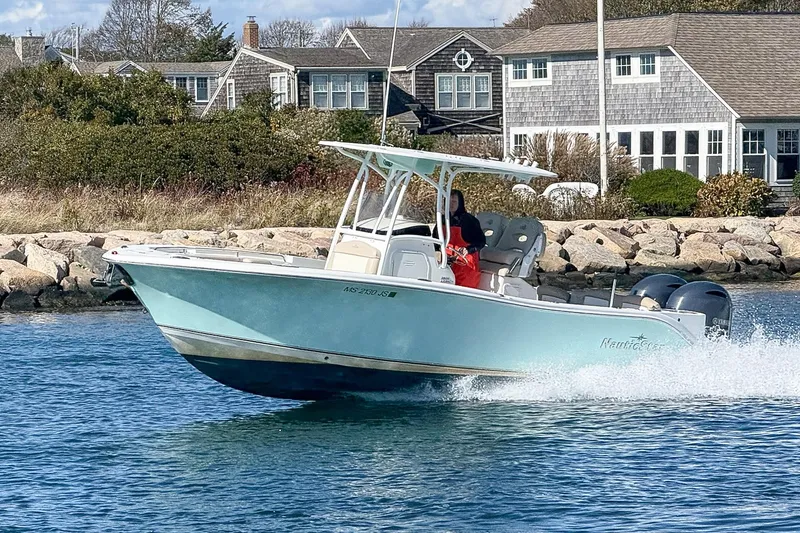 Slide: The Image of 2017 NauticStar 2602 Legacy boat cruising near coastal homes. - 1