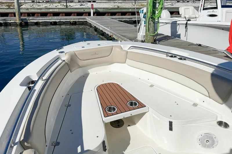 Slide: The Image of 2017 NauticStar 2602 Legacy boat interior with seating and wooden table at dock. - 11