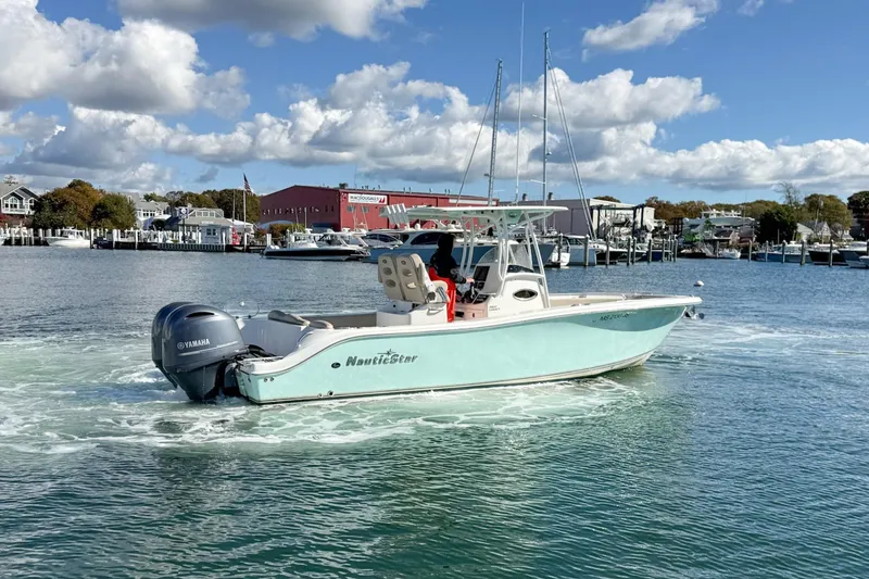 Slide: The Image of 2017 NauticStar 2602 Legacy boat cruising in a marina with Yamaha engine. - 2