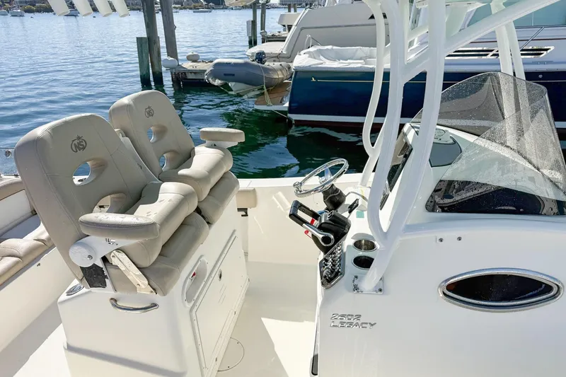 Slide: The Image of 2017 NauticStar 2602 Legacy boat interior with helm and seating at marina. - 8