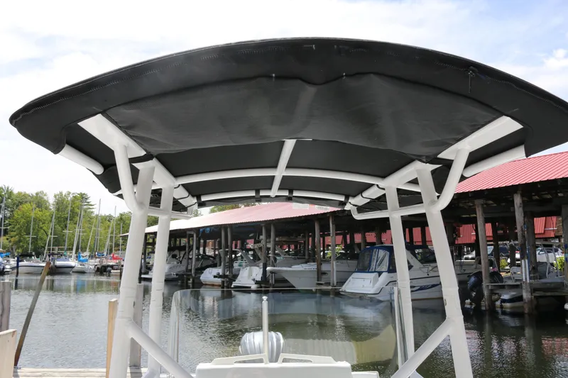 Slide: The Image of 2026 Wellcraft 202 Fisherman boat with canopy at marina, surrounded by docked boats. - 11