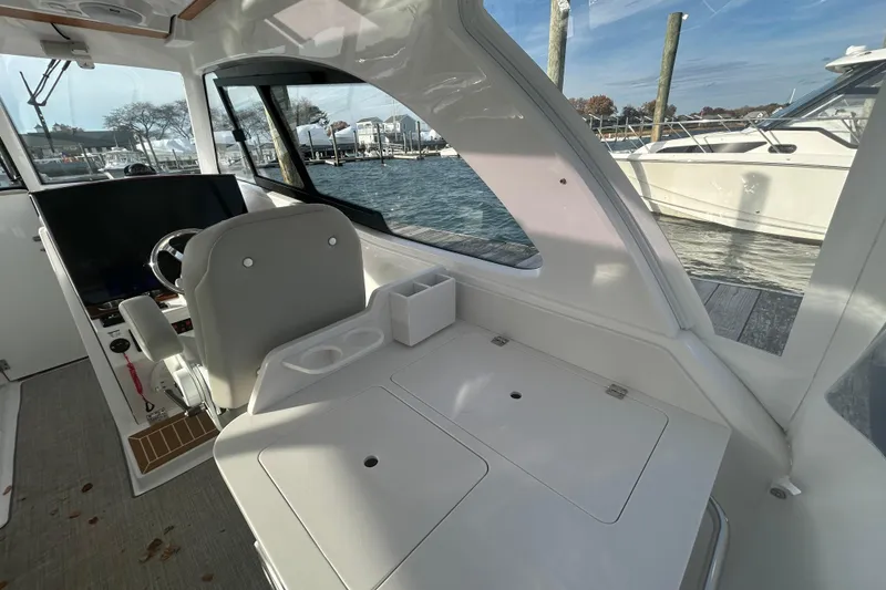 Slide: The Image of Interior of 2025 Southport 33 DC boat, featuring helm and seating area by the dock. - 4