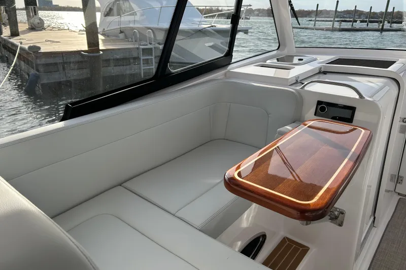 Slide: The Image of 2025 Southport 33 DC boat interior with white seating and wooden table by the water. - 5