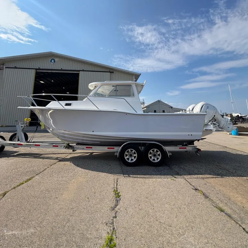 The Image of 2026 NorthCoast 255 HT boat on trailer, parked outside a large warehouse. - 0