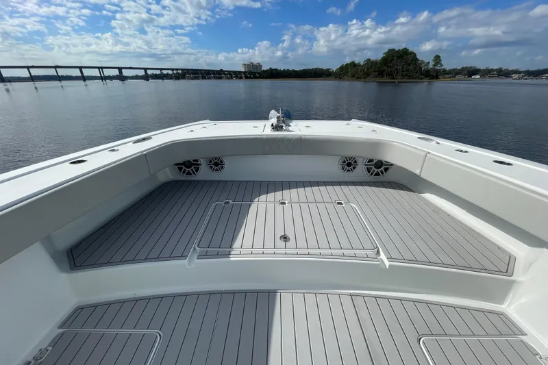 Slide: The Image of Freeman 47 boat deck, 2022 model, on calm water with bridge and trees in background. - 23