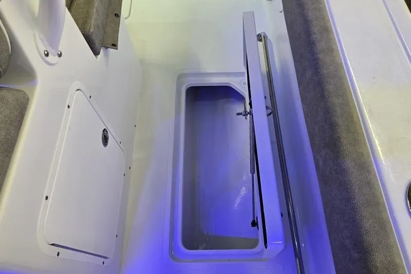 Slide: The Image of 2026 Sea Hunt Ultra 285 SE boat storage compartment with open hatch and blue lighting. - 11