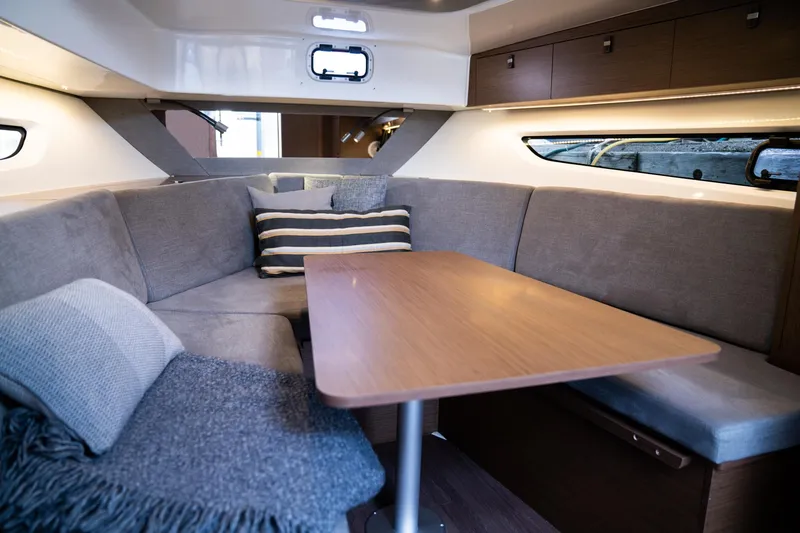 Slide: The Image of 2024 Beneteau Gran Turismo 32 Inboard interior with cozy seating and wooden table. - 16
