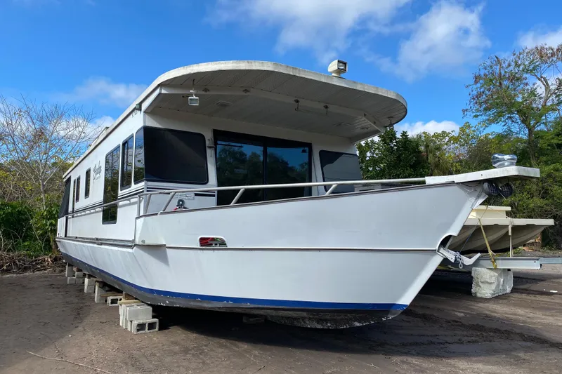 Slide: The Image of 1997 Monticello River Yacht, 60-foot, white exterior, docked on land under blue sky. - 0