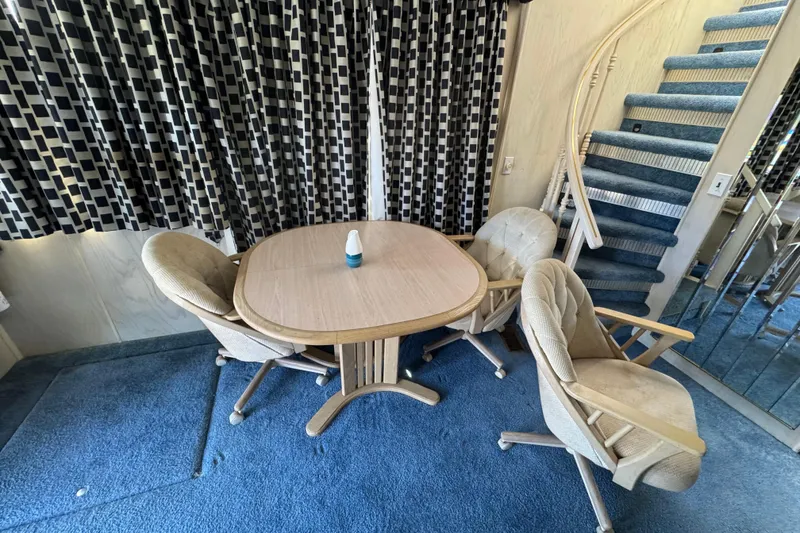 Slide: The Image of Dining area in 1997 Monticello River Yacht with table, chairs, and spiral staircase. - 1
