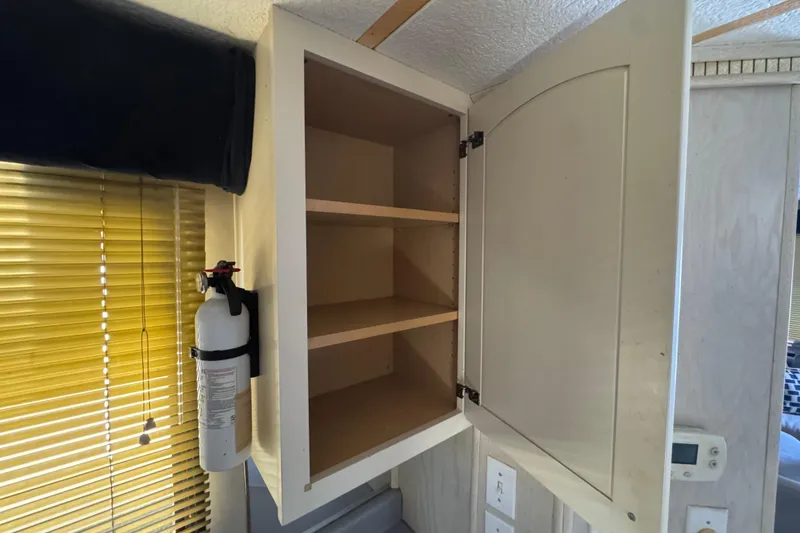 Slide: The Image of Open cabinet with shelves and fire extinguisher on Monticello River Yacht, 1997 model. - 12