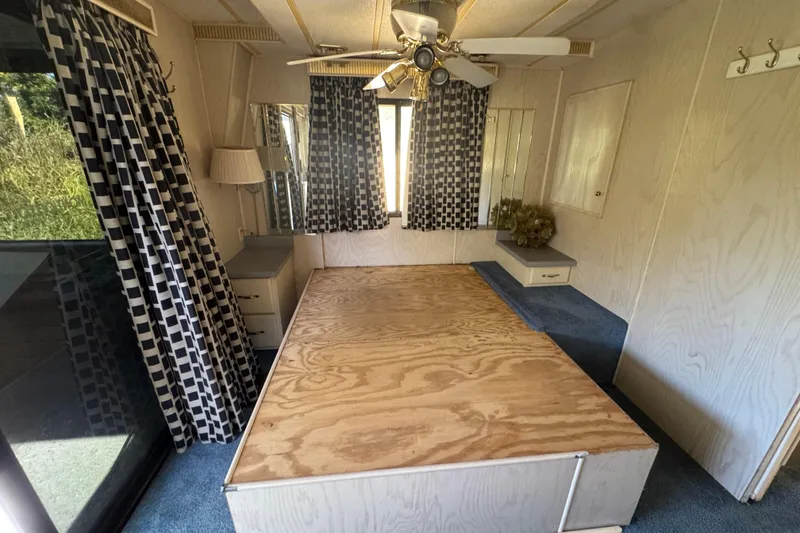 Slide: The Image of Interior of 1997 Monticello River Yacht with bed, checkered curtains, and ceiling fan. - 13