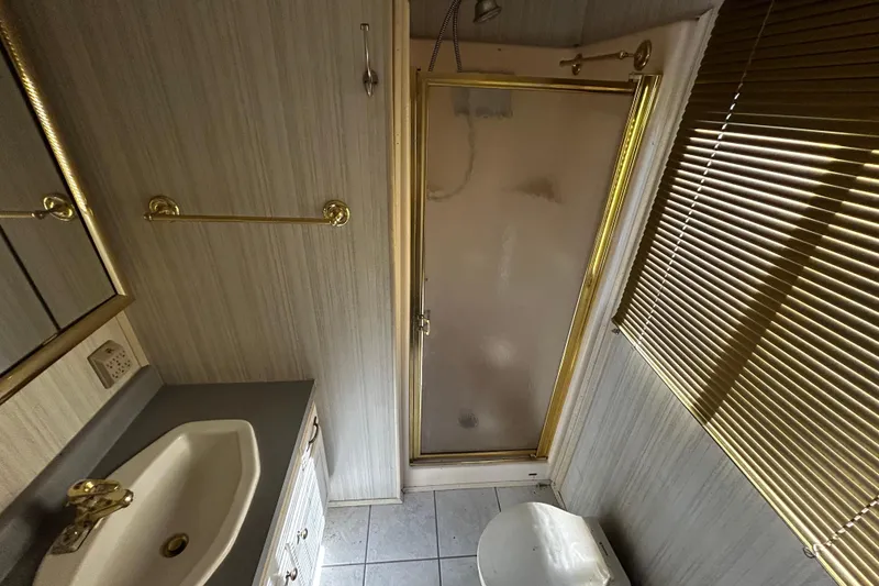 Slide: The Image of Bathroom interior of 1997 Monticello River Yacht, featuring shower, sink, and blinds. - 15