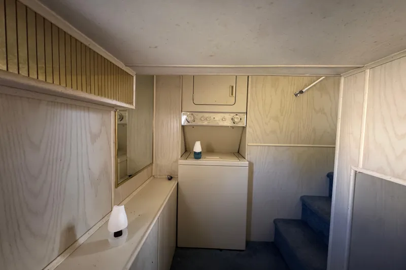 Slide: The Image of Laundry area inside 1997 Monticello River Yacht, featuring washer-dryer and wooden paneling. - 20