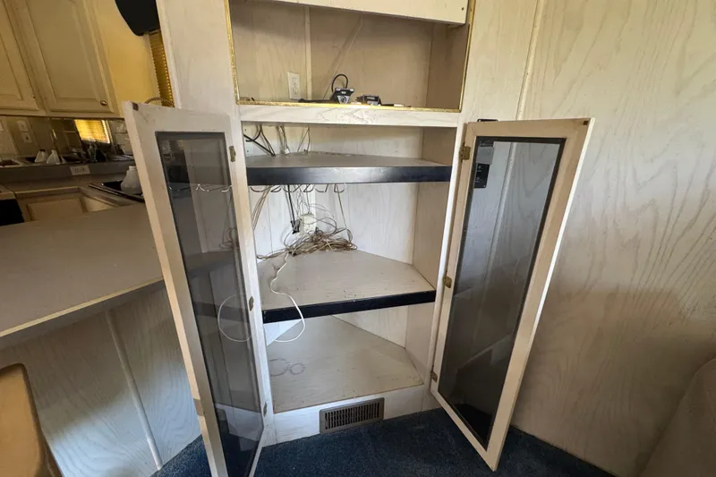Slide: The Image of Open cabinet with glass doors and shelves inside a 1997 Monticello River Yacht. - 21