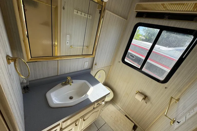 Slide: The Image of Bathroom interior of a 1997 Monticello River Yacht, featuring a sink, mirror, and window. - 23