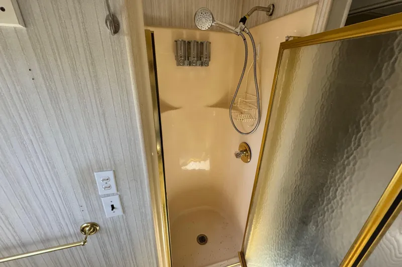 Slide: The Image of Shower area in 1997 Monticello River Yacht, featuring gold trim and handheld showerhead. - 24