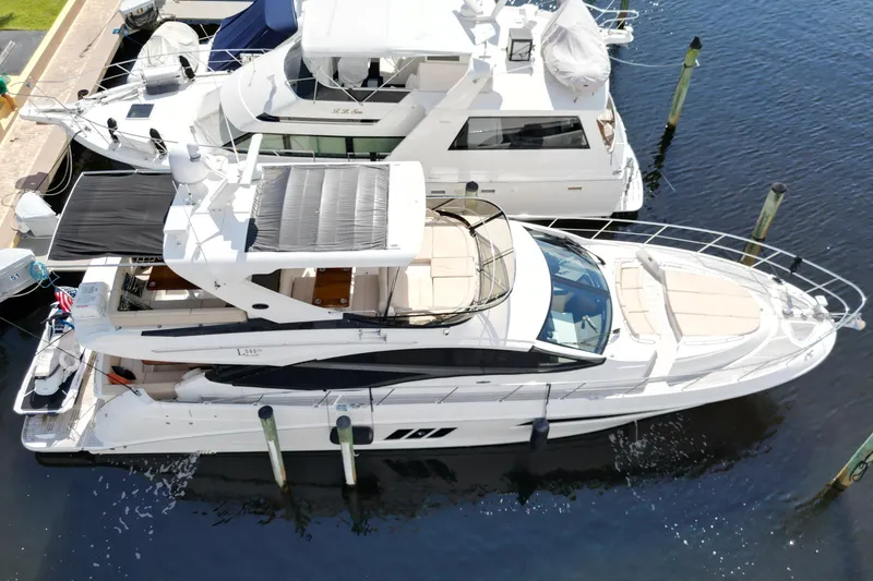 Slide: The Image of Luxurious 2016 Sea Ray L590 Fly yacht docked, surrounded by palm trees and waterfront buildings. - 25