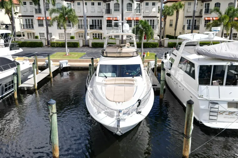 Slide: The Image of 2016 Sea Ray L590 Fly yacht docked at marina, surrounded by palm trees and waterfront buildings. - 26