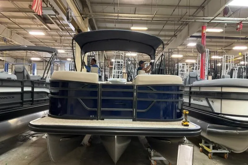 Slide: The Image of 2026 Bennington 22 SSRSE pontoon boat in a showroom, featuring a sleek design and canopy. - 5