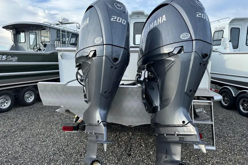 Slide: The Image of Twin Yamaha 200 engines on a 2026 Hewescraft 270 Alaskan boat, parked on gravel. - 10