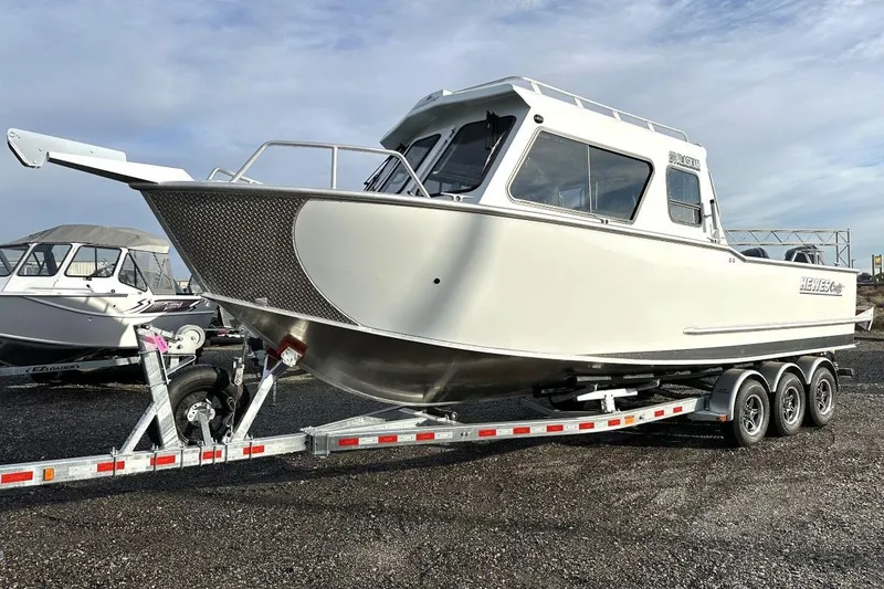 Slide: The Image of 2026 Hewescraft 270 Alaskan boat on a triple-axle trailer, parked outdoors. - 2