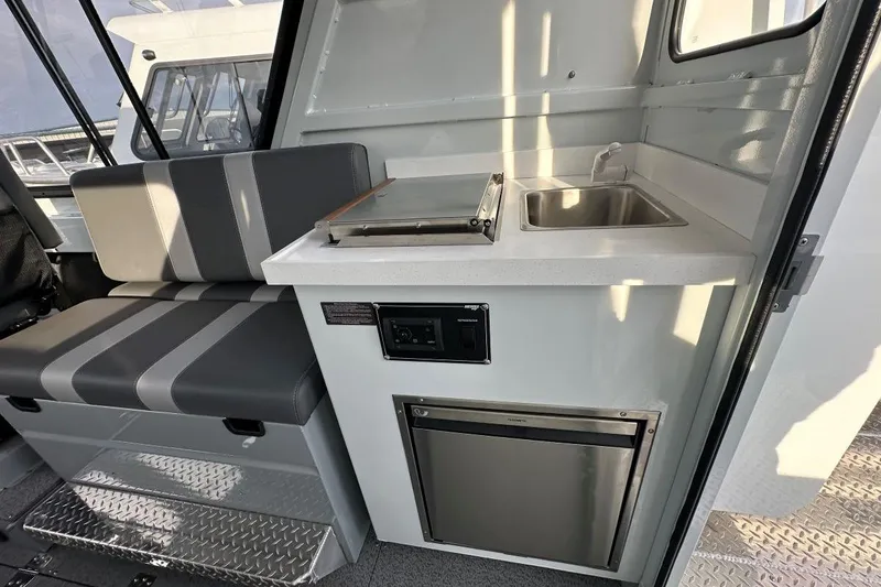 Slide: The Image of Interior of 2026 Hewescraft 270 Alaskan boat with seating, sink, and mini-fridge. - 6