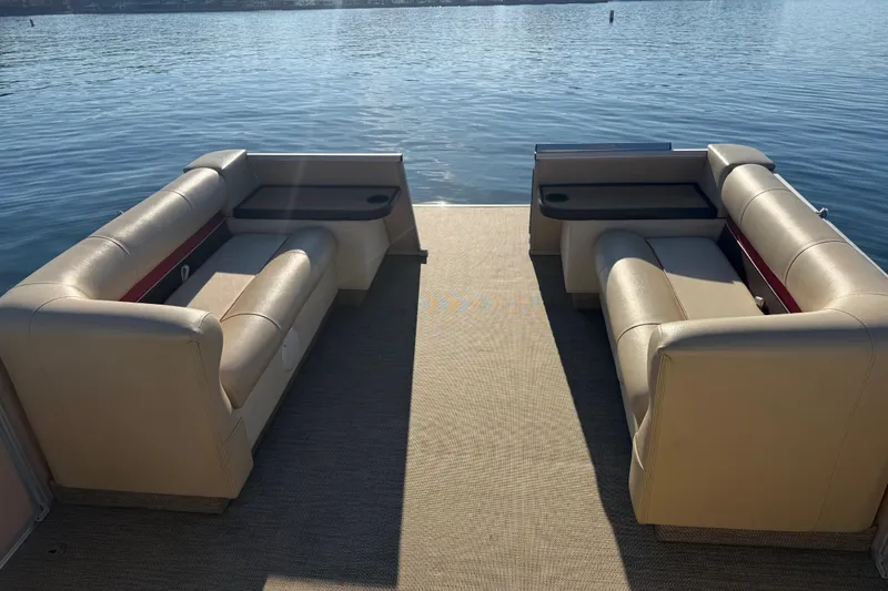 Slide: The Image of 1997 Crest CREST II DLX pontoon boat interior with beige seating on a calm lake. - 21