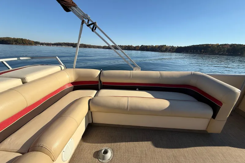 Slide: The Image of 1997 Crest CREST II DLX pontoon boat interior with beige and red seating on a lake. - 23