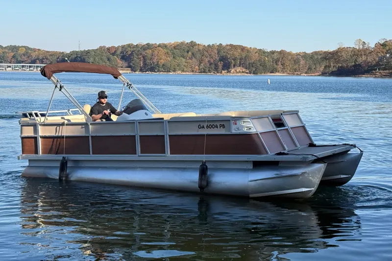 Slide: The Image of 1997 Crest CREST II DLX pontoon boat on a serene lake with a driver. - 3