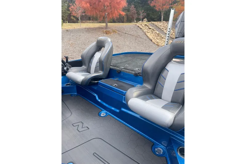 Slide: The Image of 2024 Nitro Z20 boat interior with gray and blue seats, set against a scenic autumn backdrop. - 3