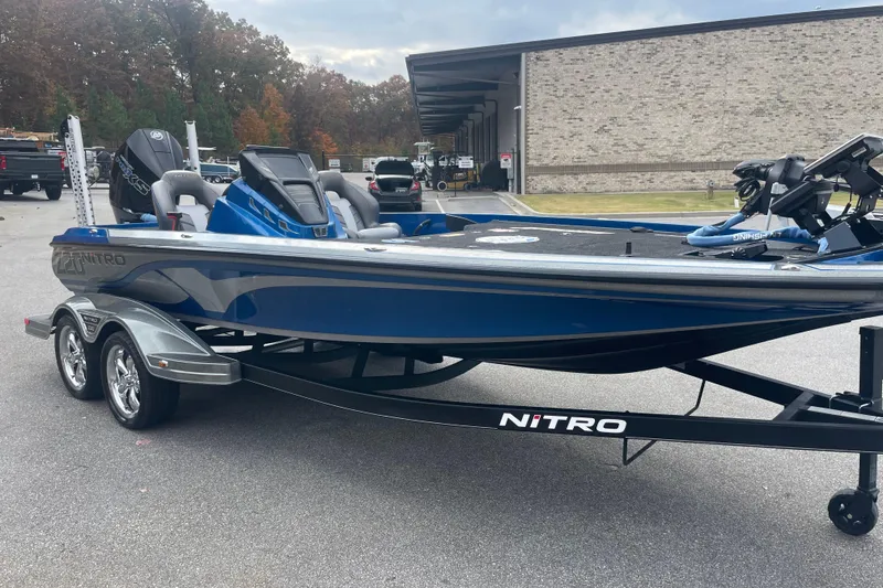 Slide: The Image of 2024 Nitro Z20 boat in blue on a trailer, parked outdoors. - 8
