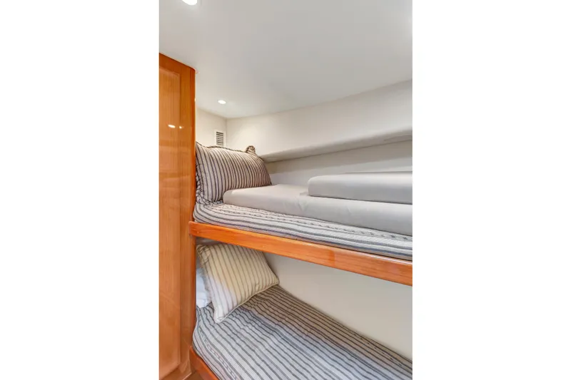 Slide: The Image of Bunk beds in 2001 Viking 50 Convertible yacht cabin, featuring striped bedding and wooden accents. - 20
