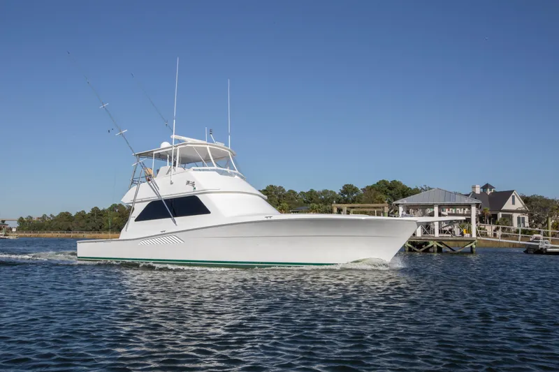 Slide: The Image of 2001 Viking 50 Convertible yacht cruising on a sunny day near waterfront homes. - 33