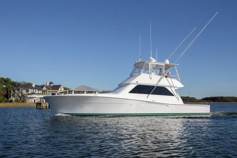 Slide: The Image of 2001 Viking 50 Convertible yacht cruising on a calm waterway near luxury homes. - 34