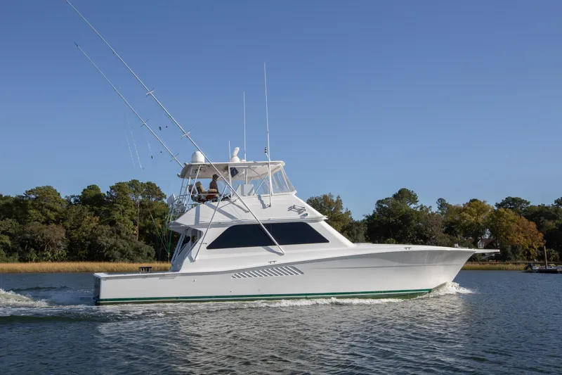 Slide: The Image of 2001 Viking 50 Convertible yacht cruising on a calm river with trees in the background. - 36