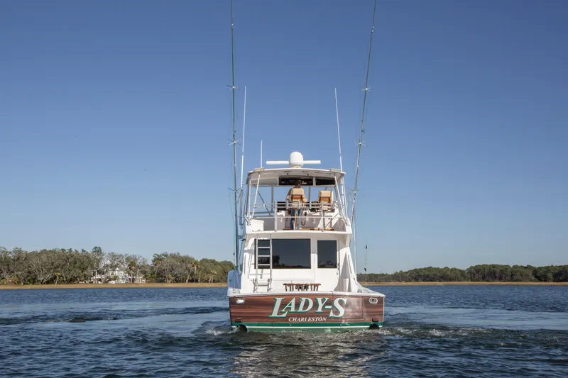 Slide: The Image of 2001 Viking 50 Convertible yacht on water, rear view, clear sky, trees in background. - 38