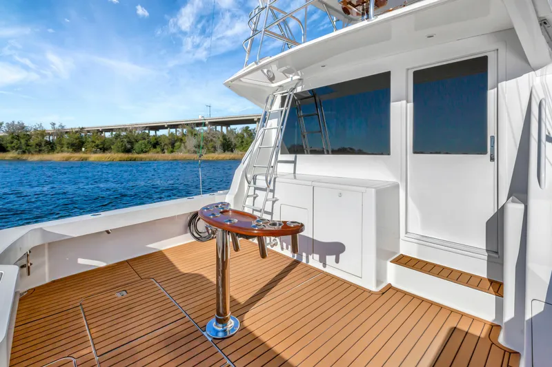 Slide: The Image of 2001 Viking 50 Convertible yacht deck with ladder, wooden flooring, and scenic water view. - 7