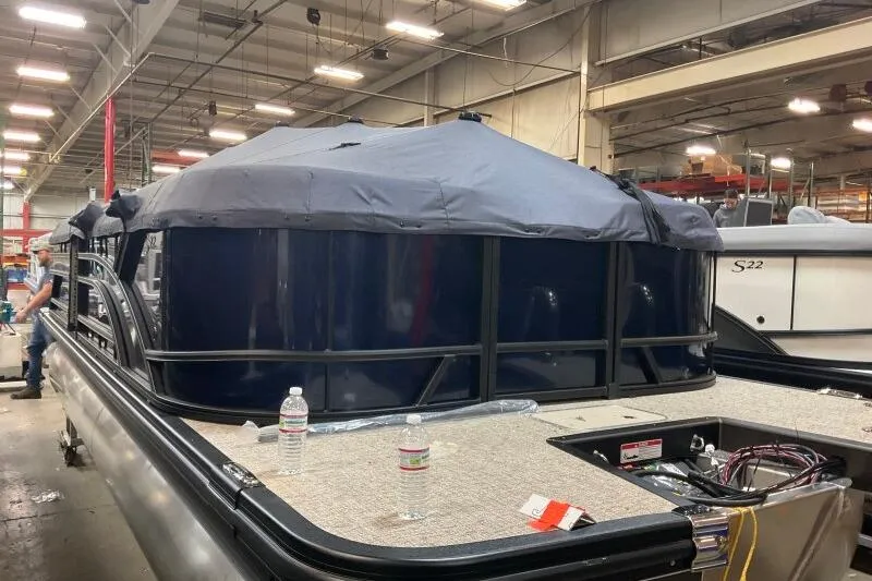Slide: The Image of 2026 Bennington 22 SSRSE pontoon boat in a factory setting, partially covered. - 2