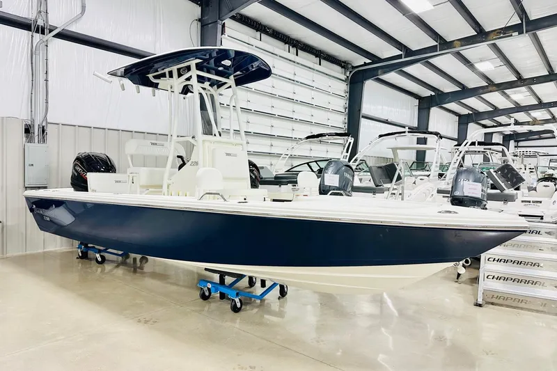 The Image of 2026 Pathfinder 2200 TRS boat in showroom, blue hull, center console, indoor display. - 2