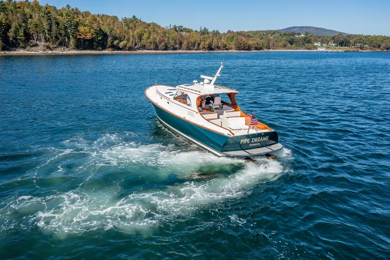 Slide: The Image of Hinckley Talaria 44 Express 2002 cruising on a scenic lake with forested shoreline. - 11