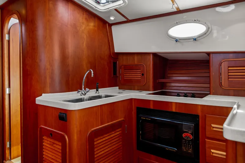 Slide: The Image of Luxurious 2002 Hinckley Talaria 44 Express yacht kitchen with wood cabinetry and modern appliances. - 34