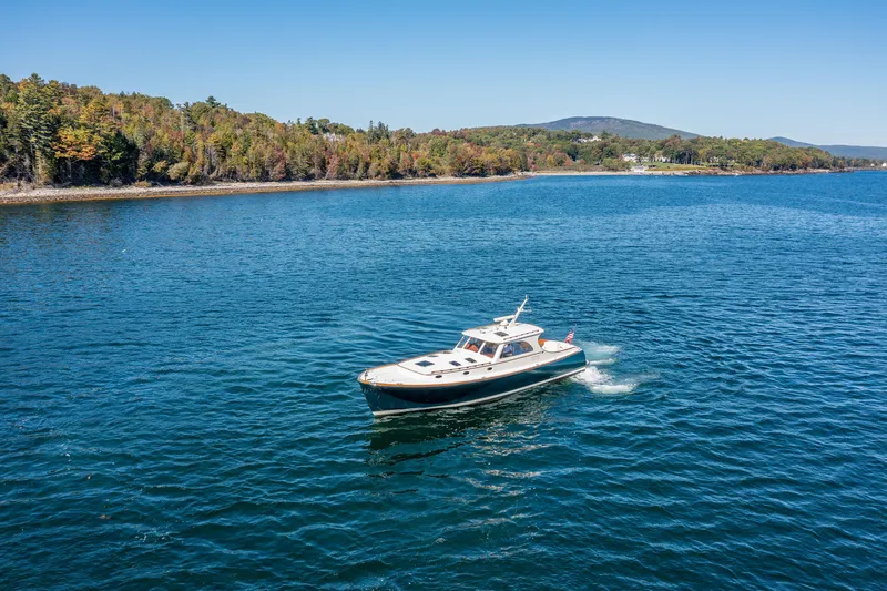 Slide: The Image of 2002 Hinckley Talaria 44 Express cruising on a scenic lake with forested shoreline. - 4