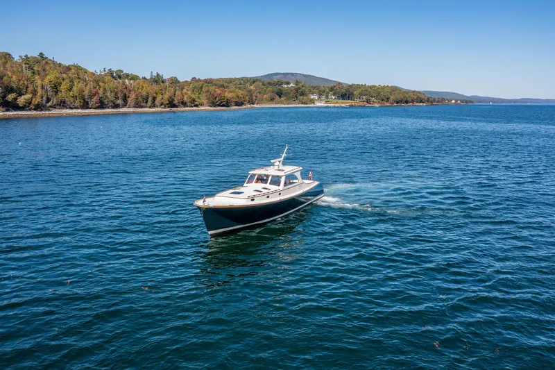 Slide: The Image of 2002 Hinckley Talaria 44 Express cruising on a scenic lake with forested shoreline. - 5