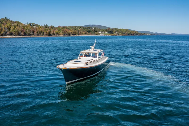 Slide: The Image of 2002 Hinckley Talaria 44 Express cruising on a scenic lake with forested shoreline. - 7