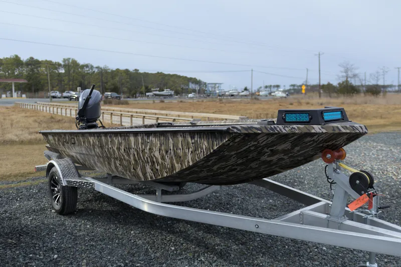 Slide: The Image of 2026 Avid 16 Commander boat on trailer, camo design, parked outdoors. - 11