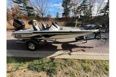 Slide: The Image of 2017 Nitro Z18 fishing boat on trailer, parked outdoors with trees in background. - 2