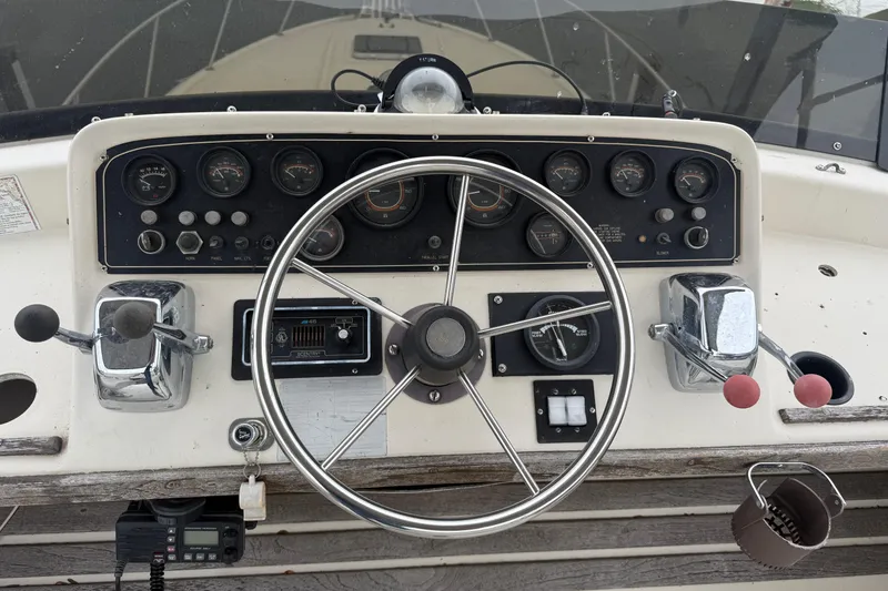 Slide: The Image of 1986 Silverton 34 Convertible boat dashboard with steering wheel and control panel. - 11